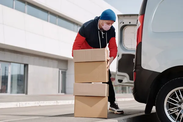Repartidor de delivery sonriendo junto a su moto propia