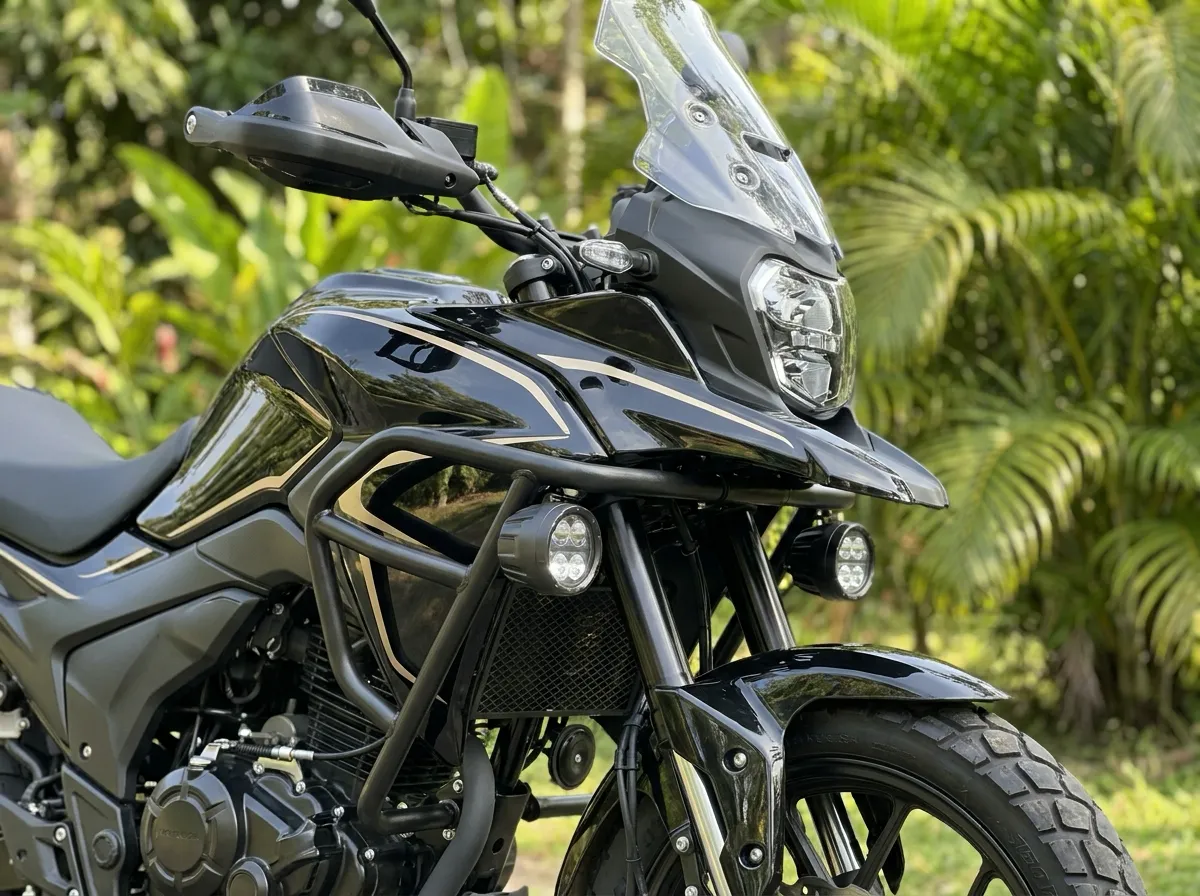Detalle del tanque negro con franjas doradas, el faro LED, el parabrisas y los neblineros de una moto adventure de 250cc