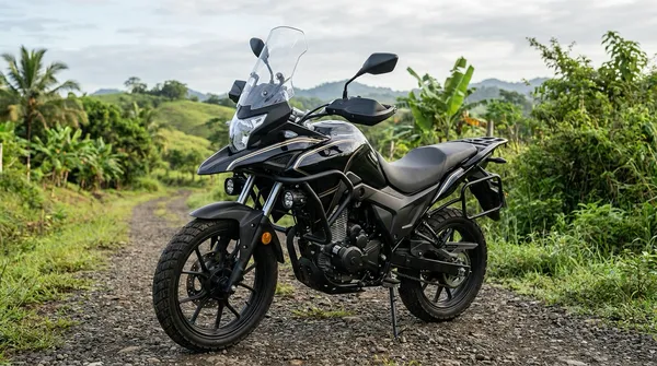 Moto adventure negra con franjas doradas, parabrisas y defensas, estacionada en un camino de grava entre colinas verdes del interior de Panamá