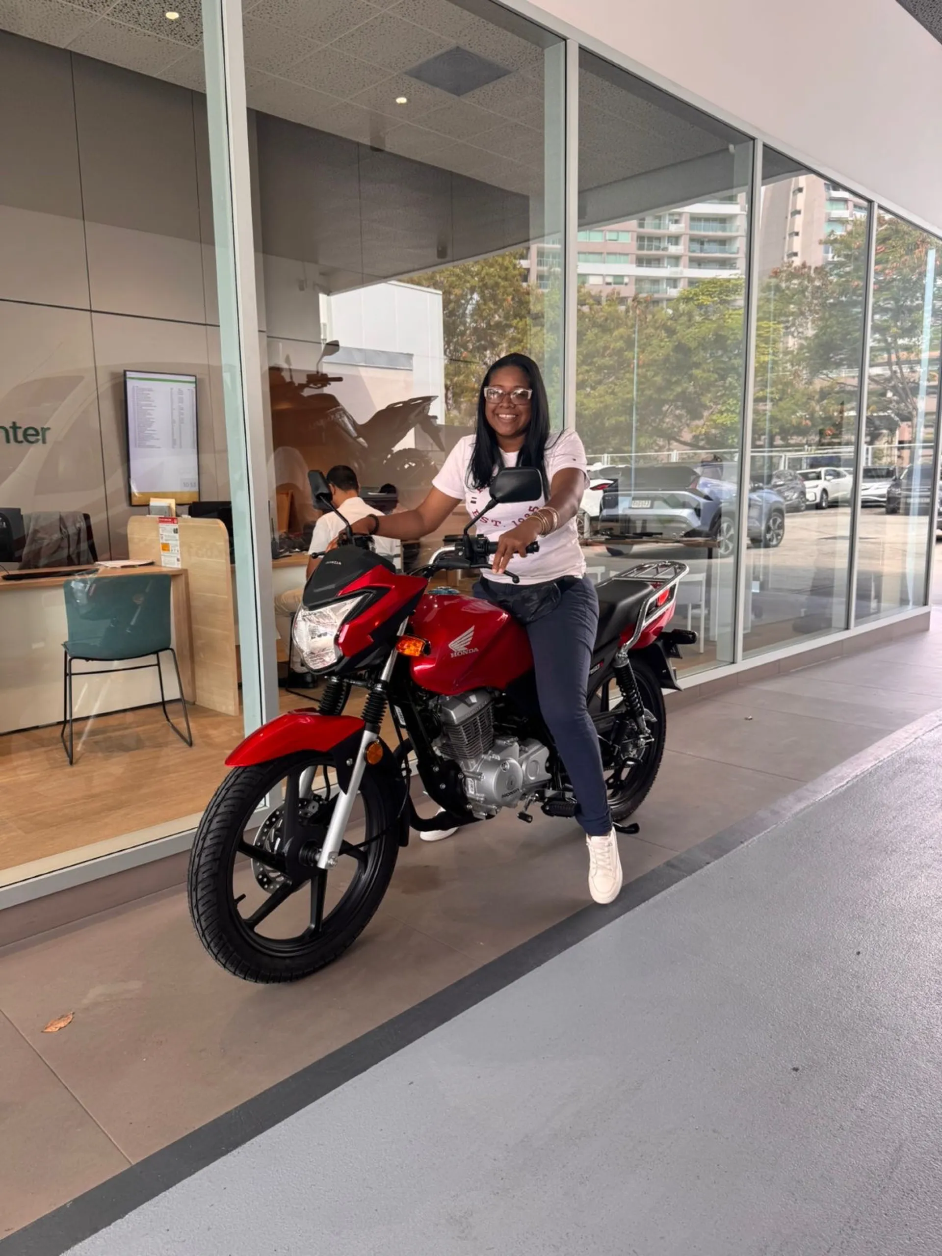 Clienta feliz con su moto Honda roja financiada en Panamá